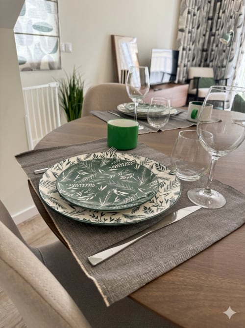 Elegante mesa posta na Villa Sotto Mayor, Figueira da Foz, com pratos decorados com padrão de folhas verdes e taças de vinho
