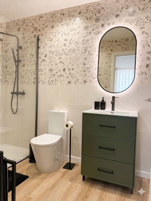 Banheiro moderno na Villa Sotto Mayor com armário verde, espelho oval, papel de parede floral, chuveiro espaçoso e piso em madeira