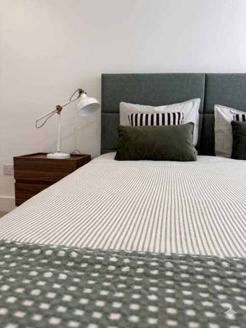 Quarto moderno na Villa Sotto Mayor em Figueira da Foz com cama de listras, cabeceira estofada cinza e luminária