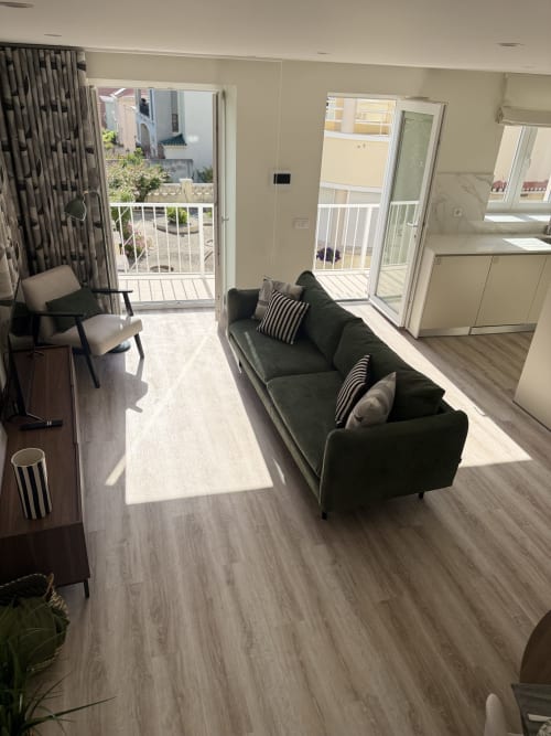 Moderna sala de estar com vista para o mar na Villa Sotto Mayor, sofá escuro, assoalho em madeira e acesso a varanda em Figueira da