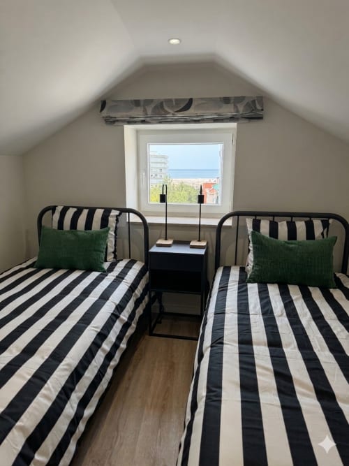 Quarto duplo com roupa de cama às riscas na Villa Sotto Mayor, Figueira da Foz, com vista para o mar