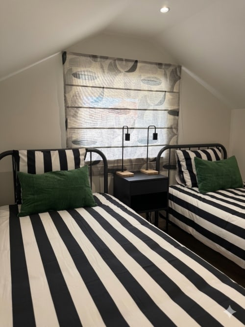 Quarto aconchegante na Villa Sotto Mayor com camas gêmeas, roupa de cama listrada, almofadas verdes e vista para o mar em Figueira da Foz
