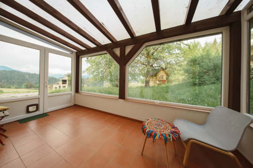 Garden Suite sunroom at Kmetija Pečnik with views of countryside, wooden beams, terracotta floor, and modern furnishings in