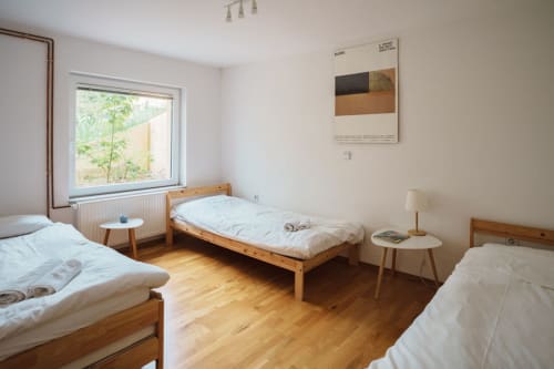 Bright triple bedroom at Kmetija Pečnik with wooden beds, window view, and modern furnishings in Prevalje