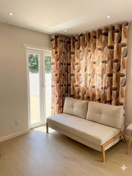 Apartamento bege com sofá creme e cortinas estampadas, portas de vidro com vista para o jardim em Villa Sotto Mayor, Figueira da Foz