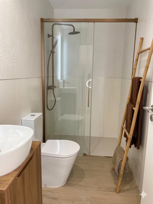 Banheiro moderno da Villa Sotto Mayor, apartamento Casa Ninho com box de vidro, vasos branco e móveis em madeira