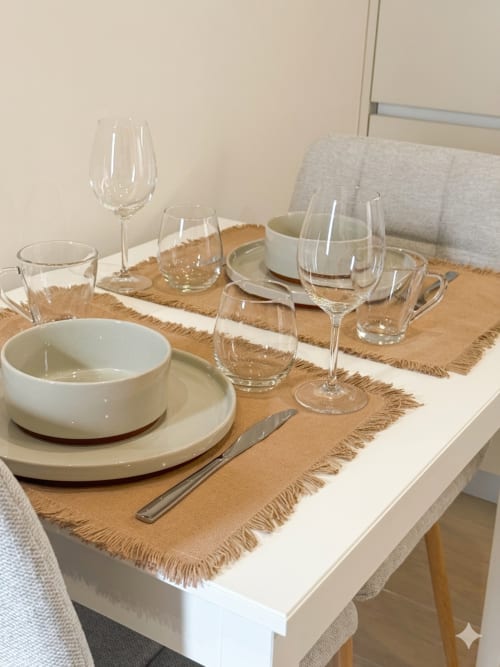 Mesa de refeições elegante na Villa Sotto Mayor, Figueira da Foz, com pratos brancos, taças de vinho e superfície bege natural