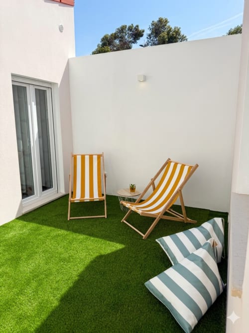 Terraço ensolarado do apartamento Casa Vizo em Villa Sotto Mayor, Figueira da Foz com espreguiçadeiras listradas e relva artificial