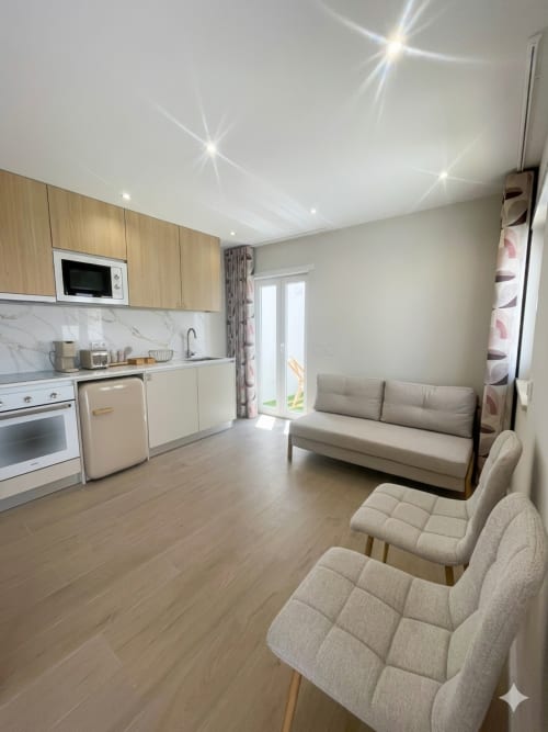 Apartamento moderno em Villa Sotto Mayor, Figueira da Foz: sala integrada com cozinha, sofá e acesso à vista de mar