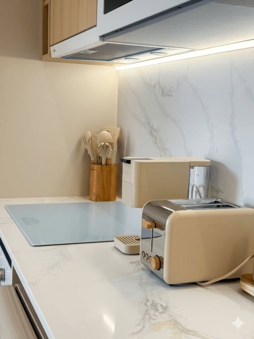 Bancada de cozinha moderna na Villa Sotto Mayor em Figueira da Foz com painel de mármore, torradeira e utensílios de madeira