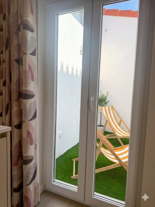 Portas de vidro abertas para um pátio ensolarado com espreguiçadeiras listradas no apartamento Villa Sotto Mayor, Figueira da Foz