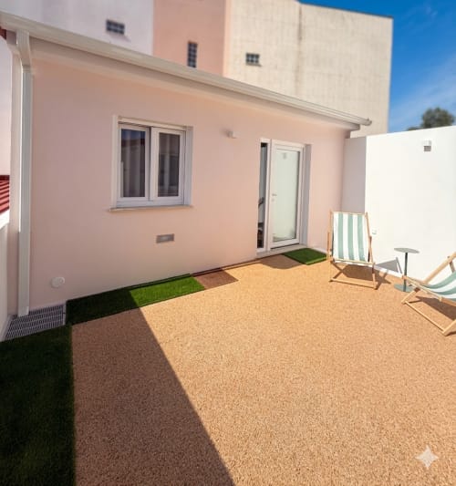 Quarto com paredes rosa, pátio com espreguiçadeiras e jardim arenoso na Villa Sotto Mayor, Figueira da Foz
