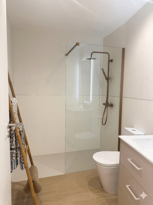Banheiro moderno da Villa Sotto Mayor, Figueira da Foz com box de vidro, sanitário branco, gabinete em madeira e vista para o mar