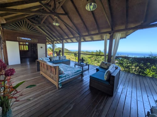 Terrasse en plein air de Fare Tihi Moana avec vue sur l'océan, pont en bois, salon et paysage tropical à Uturoa