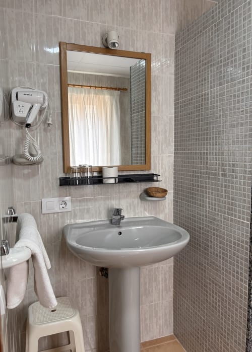 Baño moderno con lavamanos pedestal, espejo enmarcado y ducha pequeña en Hostal Las Dunas de Cabo de Gata