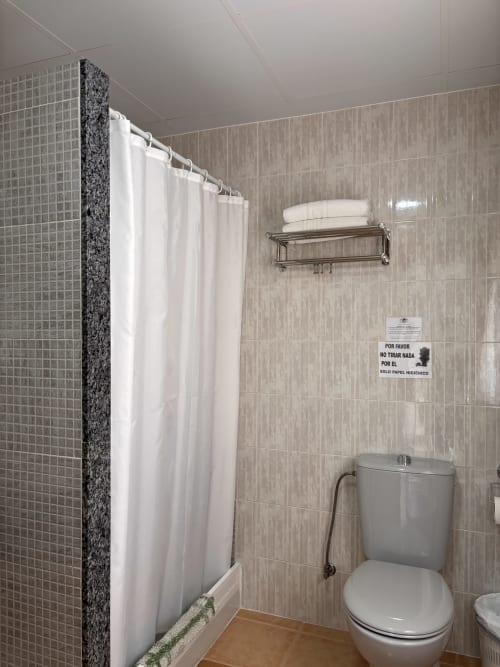 Baño limpio con cortina de ducha blanca y sanitario en Hostal Las Dunas, Cabo de Gata, Almería