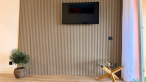 Interior moderno de apartamento en Holidays Costa Brava con revestimiento de madera vertical, TV de pantalla plana, planta en maceta y