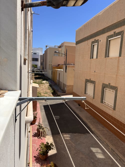 Vista desde el balcón de un estrecho callejón entre edificios color arena en Hostal Las Dunas, Cabo de Gata, Almería