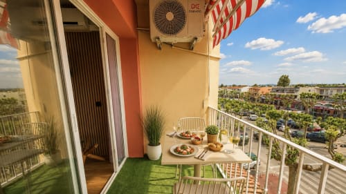 Balcón soleado en Holidays Costa Brava Empuriabrava con zona de comedor, vistas a la ciudad y toldo a rayas rojas