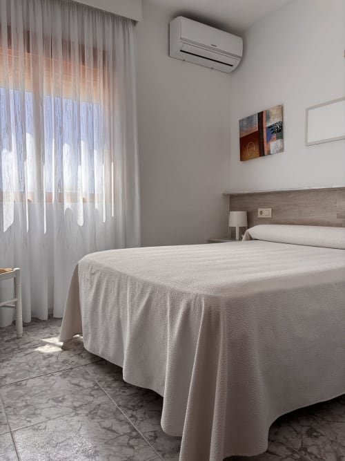 Habitación Single Superior luminosa en Hostal Las Dunas con cama, aire acondicionado y luz natural por cortinas translúcidas