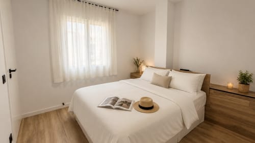 Luminosa habitación en Holidays Costa Brava con ropa de cama blanca, tocador de madera y cortinas translúcidas en Empuriabrava