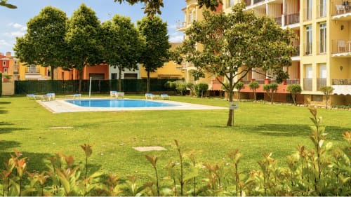 Exuberante jardín con piscina en Holidays Costa Brava, Empuriabrava. Apartamentos coloridos con vistas al césped verde y zona de descanso