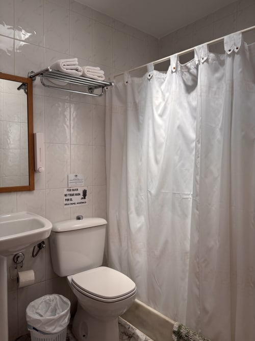 Baño limpio en Hostal Las Dunas con ducha, inodoro, lavabo y toallas blancas en Cabo de Gata