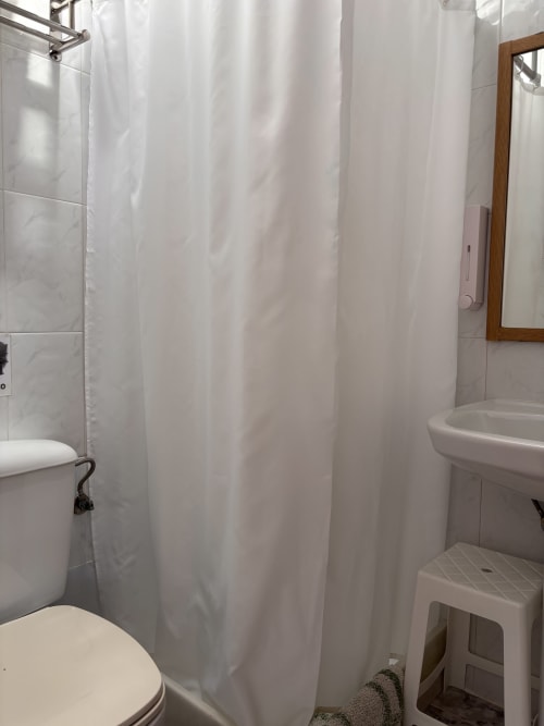 Baño de Hostal Las Dunas con cortina de ducha blanca, inodoro, lavamanos y taburete en Cabo de Gata