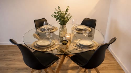Elegante mesa de comedor redonda en Holidays Costa Brava con cubiertos, copas de vino y flores frescas en Empuriabrava
