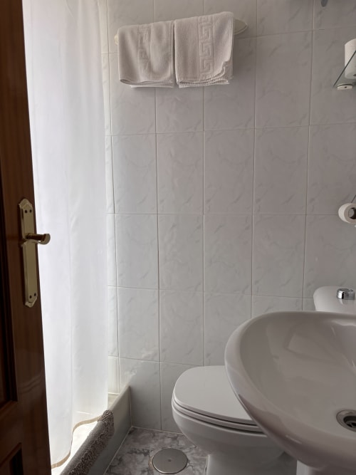 Baño limpio con azulejos blancos, lavabo, inodoro y toalla en habitación Single Superior del Hostal Las Dunas, Cabo de Gata Almería
