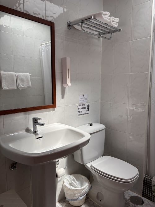 Baño moderno en Hostal Las Dunas, Cabo de Gata: lavabo blanco, inodoro, ducha, espejo y toallero