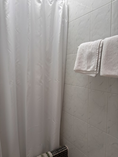 Baño limpio y luminoso con cortina de ducha y toallas en Hostal Las Dunas, Cabo de Gata Almería