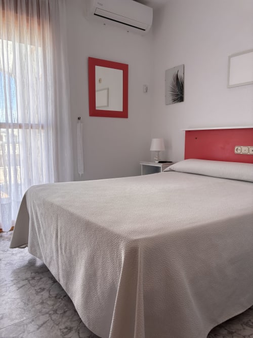 Habitación individual superior en Hostal Las Dunas, Cabo de Gata, con cabecero rojo, ropa de cama color crema y comodidades modernas