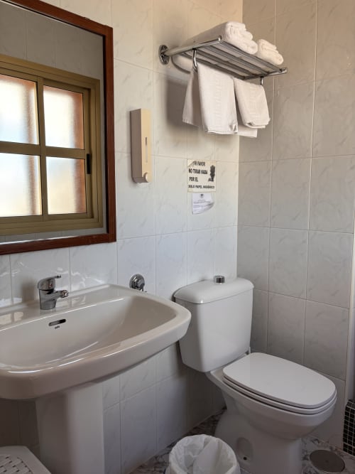 Baño limpio en Hostal Las Dunas con lavamanos blanco, inodoro, toallero y paredes alicatadas en Cabo de Gata