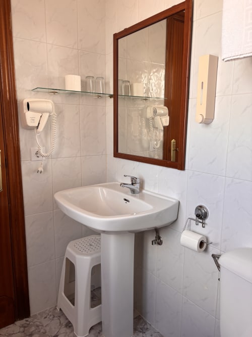 Baño limpio con lavamanos de pedestal, espejo mural y equipamiento moderno en Hostal Las Dunas, Cabo de Gata