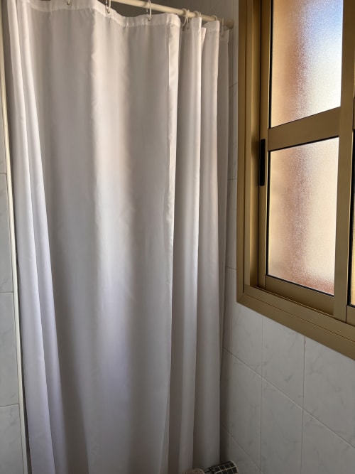 Cortina de ducha blanca en el baño de la habitación individual superior del Hostal Las Dunas, Cabo de Gata Almería