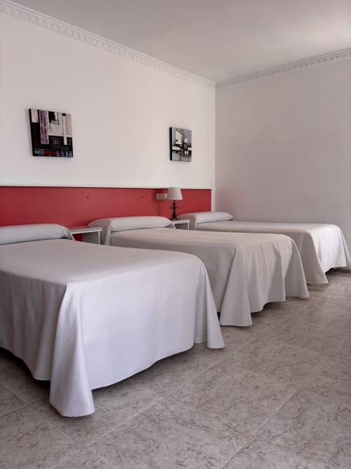 Habitación triple en Hostal Las Dunas, Cabo de Gata, con camas blancas, cabecero rojo y comodidades modernas