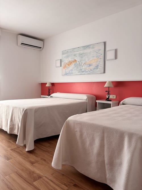 Habitación Triple Superior en Hostal Las Dunas de Cabo de Gata con dos camas, pared de acento rojo y comodidades modernas