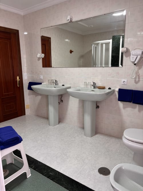 Moderno baño del Hostal Las Dunas con dobles lavabos, espejo grande, inodoro y ducha en Cabo de Gata Almería