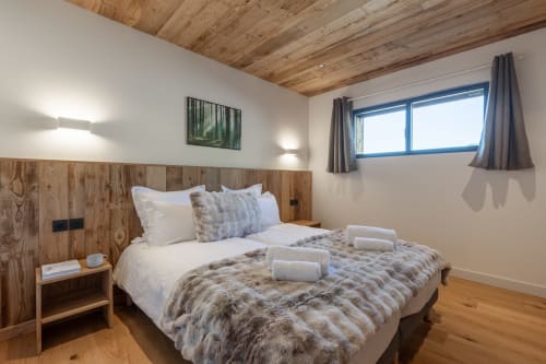Cozy bedroom in Chalet Magy, Les Gets with wooden ceiling, queen bed, and mountain views from window