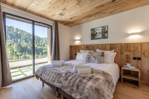 Luxurious bedroom in Altitudia Chalet Magy with wooden beams, mountain views, and modern amenities in Les Gets