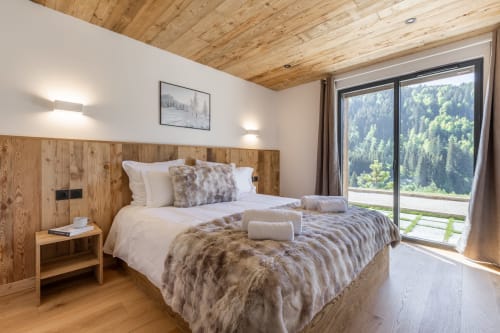 Modern wooden bedroom at Altitudia Chalet Magy with mountain forest views from balcony doors