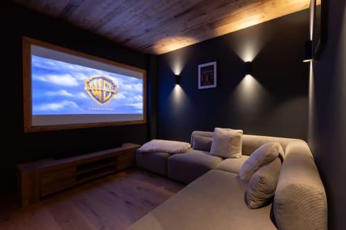 Luxury home theater room in Altitudia villa with plush sectional sofa, projector screen displaying Warner Bros logo, and