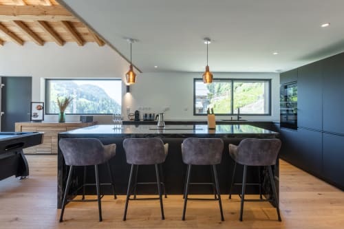 Modern luxury chalet kitchen with mountain views, black island seating, and alpine landscape at Altitudia Les Gets