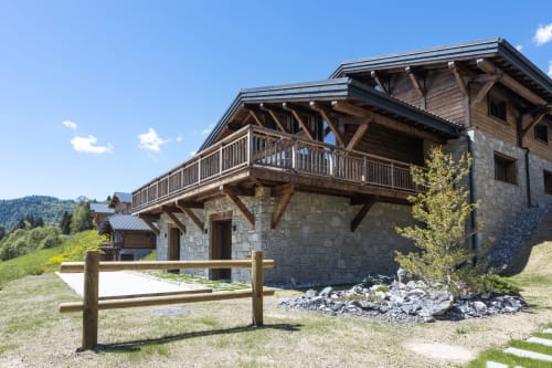 Luxury alpine chalet Magy 3 in Les Gets with stone facade, wooden balcony, and mountain views in Scionzier