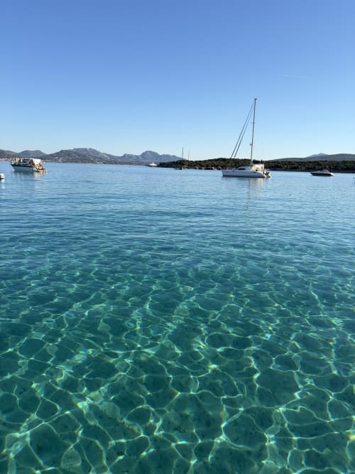 Acque turchesi cristalline con barche a vela ancorate al largo di Olbia, paesaggio costiero italiano