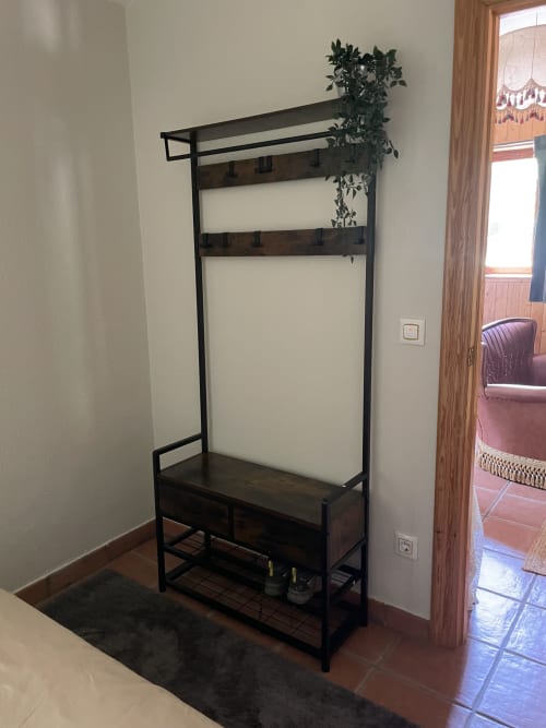Organizador de entrada metálico negro con estantes y ganchos en apartamento Monte Roblo, Salomón