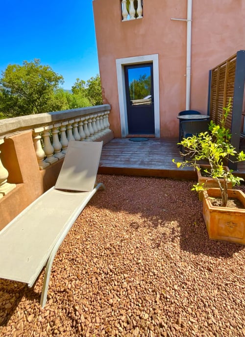 Terrasse ensoleillée du Domaine Pero Longo à Sartène avec transat, plantes en pot et vue sur les montagnes