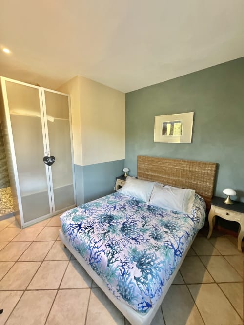 Chambre Roccapina au Domaine Pero Longo, Sartenè - lit queen-size avec tête de lit en osier, mur d'accent vert et armoire