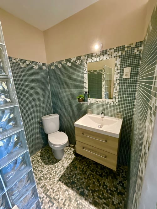 Salle de bain moderne du Domaine Pero Longo à Sartène avec carrelage mosaïque vert, lavabo blanc, toilettes et miroir